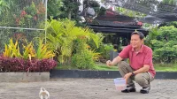 PEDULI: Rudy Susanto memberi makan salah satu burung peliharaannya. (K-TV/Ahmad Tamyizul)